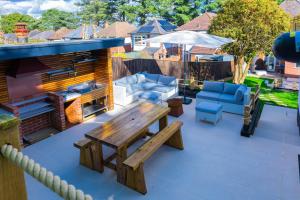 un patio con mesa de madera, sillas y parrilla en Le Chic Retreat - Luxury Hot Tub Getaway, en Bournemouth