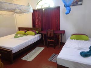 two beds in a room with a desk and a table at Wellawaya Rest House in Wellawaya