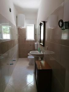 a bathroom with a sink and a toilet at Appartamento 24 letti con cucina e parcheggio privato gratuito in Candela