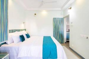 科尔瓦Captivating Tree and Garden Views One Bedroom Apartment with AC,wifi, Gym and 5min walk to beach的卧室配有一张蓝色色调的大型白色床。