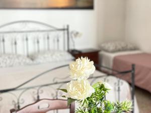 1 Schlafzimmer mit 2 Betten und einer Vase mit weißen Blumen in der Unterkunft Arco Michele in Putignano