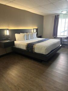 um quarto de hotel com uma cama com lençóis brancos e almofadas em Baymont by Wyndham Deming em Deming