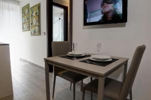 Arsenale Turin Rooms في تورينو: طاولة طعام مع كراسي وتلفزيون على الحائط