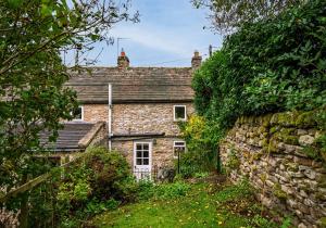 an old stone house with a stone wall at Rose Cottage in Richmond