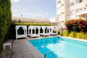 a swimming pool with white chairs next to a building at Atlántico Boutique Hotel in Punta del Este