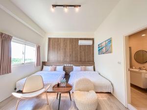 a bedroom with a bed and two chairs and a table at 沙沙民宿 in Magong