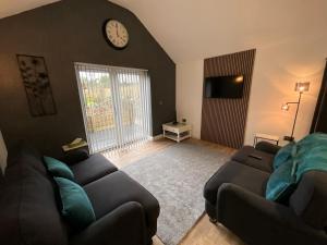a living room with a couch and a clock on the wall at The Court Yard Apartment in Cheddar