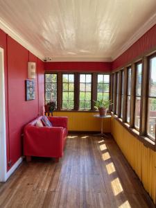 a living room with a red couch and windows at Hostal Kuyen in Pichilemu
