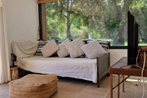 ein Schlafzimmer mit einem Bett mit Kissen und einem Fenster in der Unterkunft Villa Bergerie Baracco Argia, piscine, maquis et tradition corse pour 6 personnes in Barbaggio