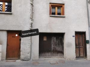 um sinal em frente a um edifício com duas portas em Coquet T1 hyper centre em Le Bourg-dʼOisans