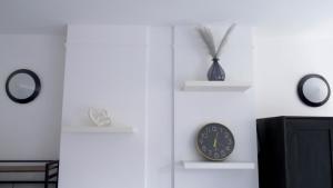 a room with three shelves and a clock on the wall at Modern Apartment in Shoreditch, City Centre in London
