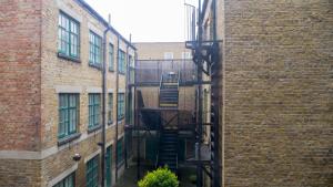 a brick alley with a fire escape between two buildings at Modern Apartment in Shoreditch, City Centre in London