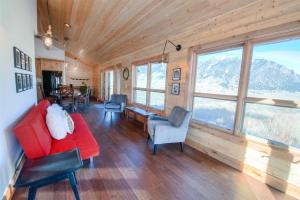 un soggiorno con divano rosso, sedie e finestre di Madison Anglers House a Cliff Lake