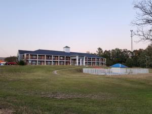 a large building with a grass field in front of it at Mississippi Hotel in Macon +4 photos
