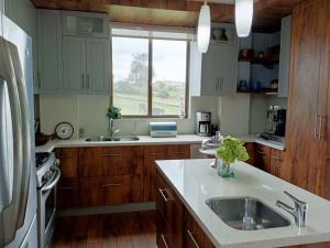 eine Küche mit Holzschränken, einem Waschbecken und einem Fenster in der Unterkunft BellaVista Casa de Montaña in Latacunga