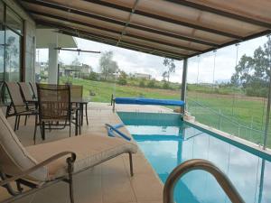 un patio con piscina, sillas y mesa en BellaVista Casa de Montaña en Latacunga