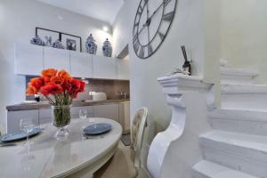 una cocina blanca con una mesa y un jarrón de flores rojas en Designer Cospicua Townhouse, en Cospicua