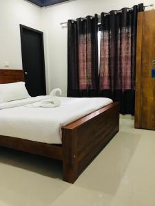 a bedroom with a bed and a window with curtains at Koshar Live in Kalpetta