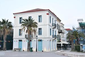 a white building with palm trees in front of it at Porto Nafplio in Nafplio