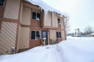 a house covered in snow with a pile of snow at Trapper Condo Unit 7 in West Yellowstone