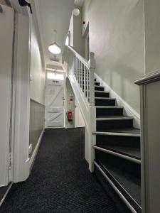 a hallway with a staircase with a white stair case at Denton House Hostel in Keswick