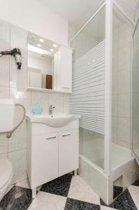 ein weißes Bad mit einem Waschbecken und einer Dusche in der Unterkunft House Rajka I in Vodice