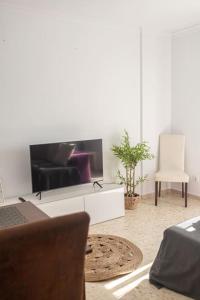 a living room with a tv and a couch and a chair at LXR Bienestar 3HAB pasos del mar in Tarifa