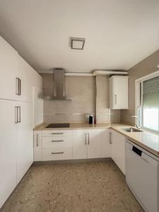 a white kitchen with white cabinets and a window at LXR Bienestar 3HAB pasos del mar in Tarifa +14 photos