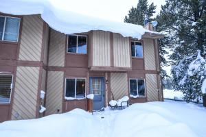a house covered in snow with a pile of snow at Trapper Condo Unit 3 in West Yellowstone