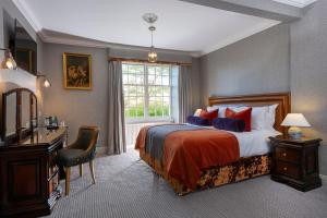 a bedroom with a bed and a desk and a window at Knipoch House Hotel in Oban