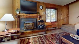 sala de estar con chimenea y TV de pantalla plana en Trapper Condo Unit 5 en West Yellowstone