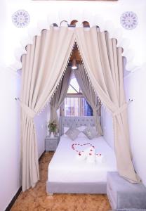 Hotel Riad Fantasia في مراكش: غرفة نوم بسرير ابيض مع ستائر