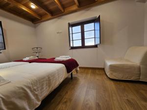 1 dormitorio con 2 camas, ventana y silla en Apartamentos Rurales Lola Penarronda, en Castropol