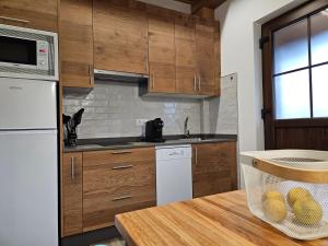 una cocina con armarios de madera y una mesa con una cesta de fruta en Apartamentos Rurales Lola Penarronda, en Castropol