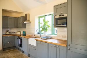 a kitchen with gray cabinets and a sink and a window at Bears Court in Cheltenham