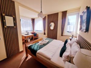 a bedroom with a bed and a desk and windows at Hotel Elisabeth Ilse in Braunlage