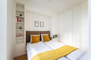 ein weißes Schlafzimmer mit einem großen Bett und gelben Kissen in der Unterkunft HM • New Studio by WU & Messe in Wien