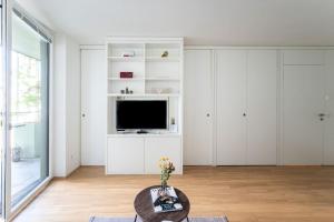 uma sala de estar branca com uma televisão e uma mesa em HM • New Studio by WU & Messe em Viena