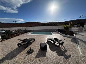 un patio con 2 bancos y una piscina en Villa Gairía, en Antigua