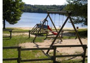 a swing set in a park next to a lake at Le village de Sèchemailles in Ambrugeat +3 photos