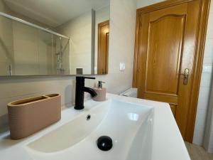 La salle de bains est pourvue d'un lavabo blanc et d'un miroir. dans l'établissement Apartamentos Montejurra, à Ayegui