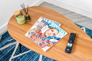 una revista y un mando a distancia sobre una mesa en 2 Bedroom Deluxe Apt - Off-Street Parking - Wifi - Netflix - 57C en Sleightholme