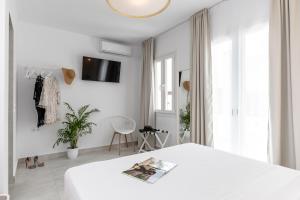 a white bedroom with a bed and a tv on the wall at Golden Bird's in Naxos Chora