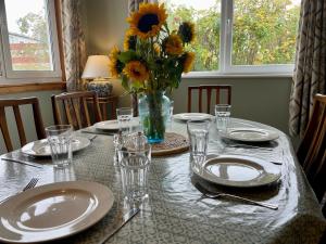 a table with plates and glasses and a vase of flowers at Peaceful Sea View Home only 5 miles from Inverness in North Kessock