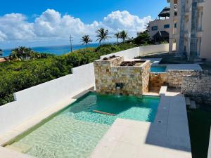 a swimming pool with the ocean in the background at Holiday apartment at La Diosa condos Isla Mujeres in Isla Mujeres