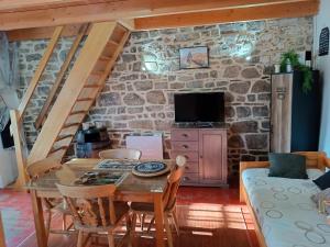 a dining room with a table and chairs and a stone wall at Petit gîte cocoon Ty Bihan Ar Feunteun in Scrignac