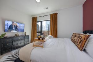 ein Schlafzimmer mit einem großen weißen Bett und einem TV in der Unterkunft Hyve - Boho Bliss - 3 Bedroom - Located In SOBRO in Nashville
