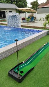 a golf club on the grass next to a swimming pool at Casa LiLa Tiny Stay & Pool Kota Bharu,free wifi,free parking 