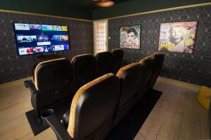 una sala de espera con sillas negras y TV de pantalla plana en Cinema & Games Room Pool Table, Hot Tub, Sleeps 15 en Saffron Walden