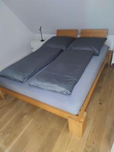ein Bett mit blauer Bettwäsche und einem Holzrahmen in der Unterkunft Ferienwohnung an der Wassermühle in Hermannsburg in Hermannsburg